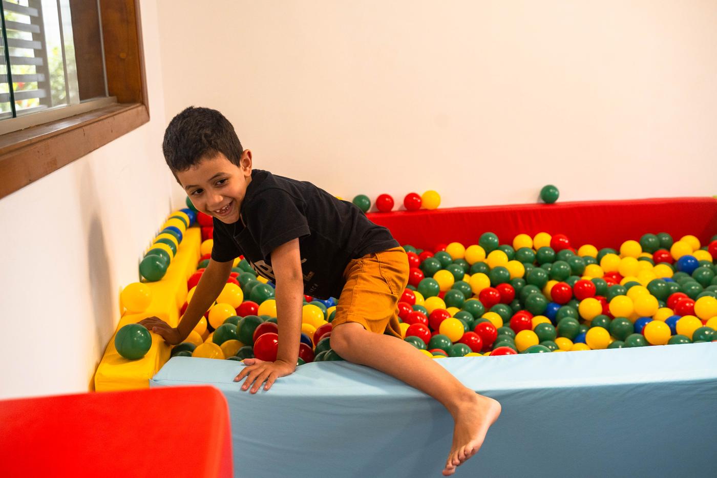Criança brincando na piscina de bolinhas do Crescer e Aprender